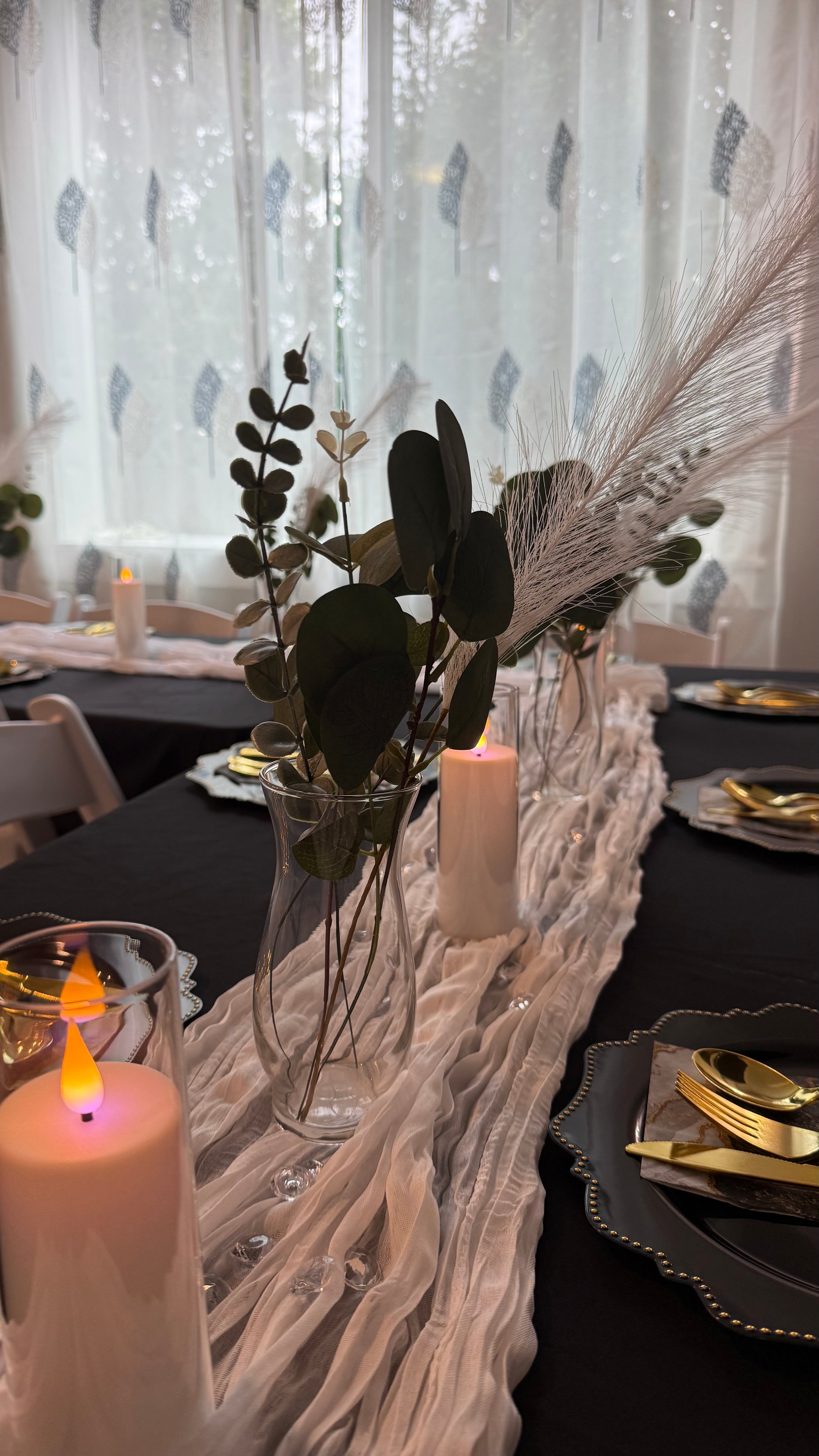 Decorative table setting with candles, flowers, and cutlery in a softly lit room.