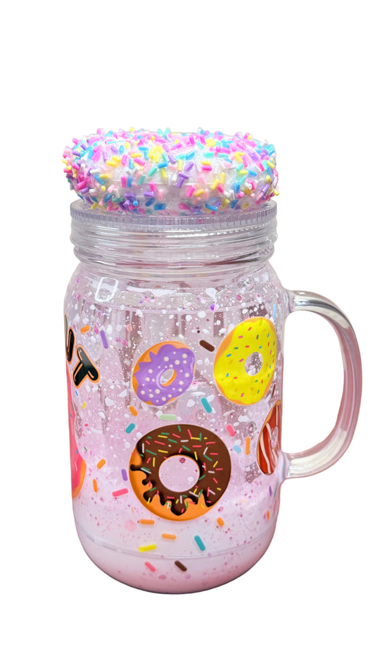 Colorful mug with donut design and sprinkles on a pink surface