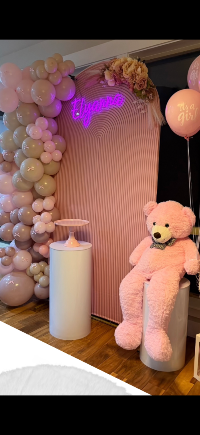 Pink teddy bear next to a balloon arch 